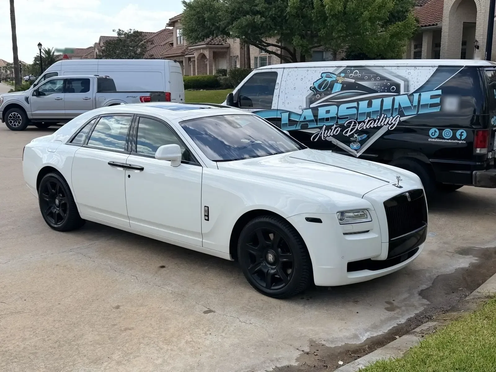 White Rolls-Royce Ghost after a mobile detail, parked beside the LabShine van on a residential street